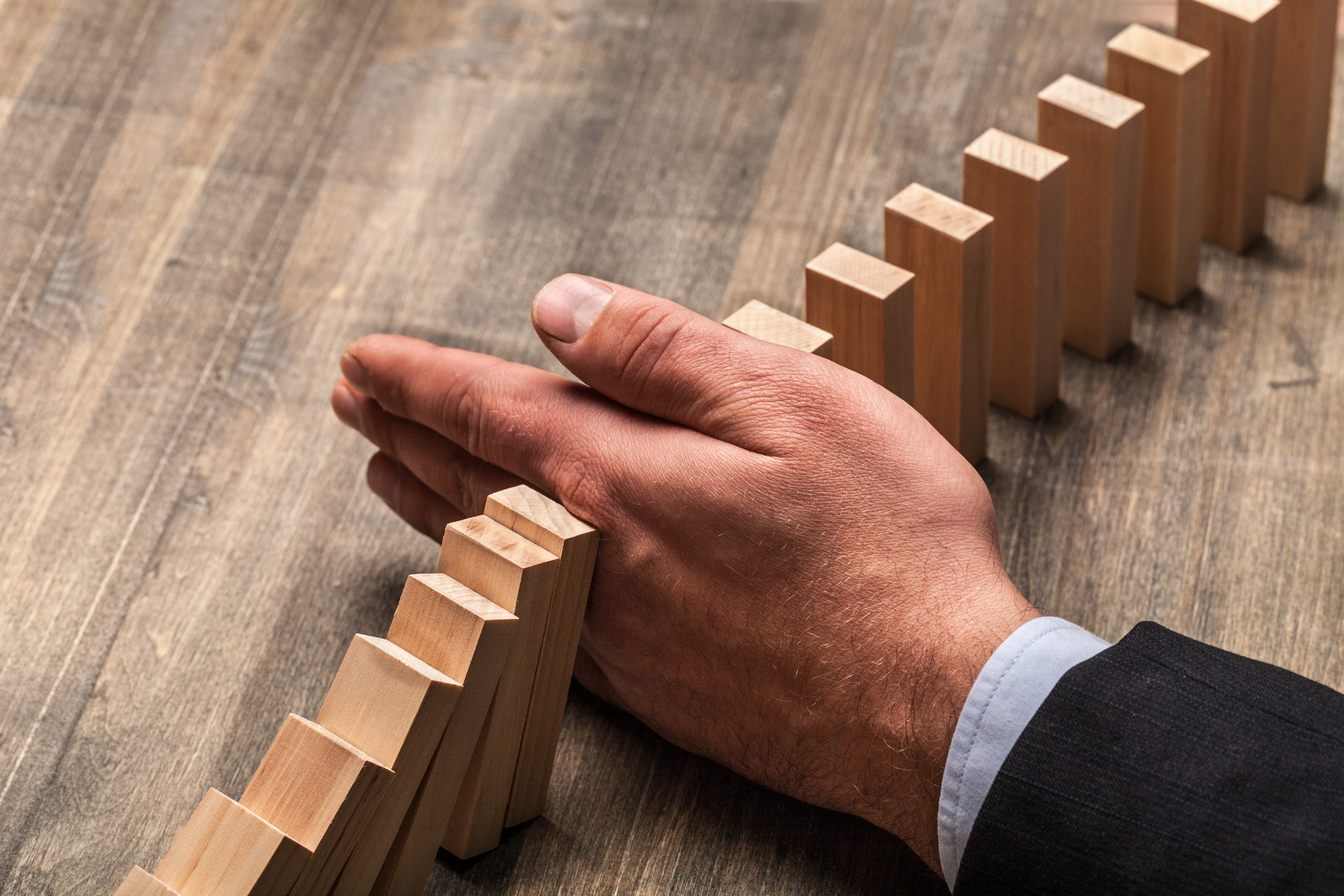 hand stopping the domino.